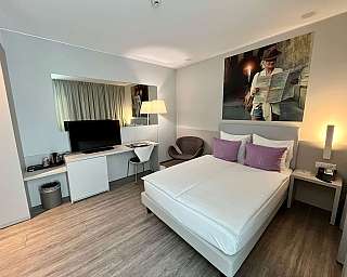 A stylish hotel room with a bed, desk, and artwork.